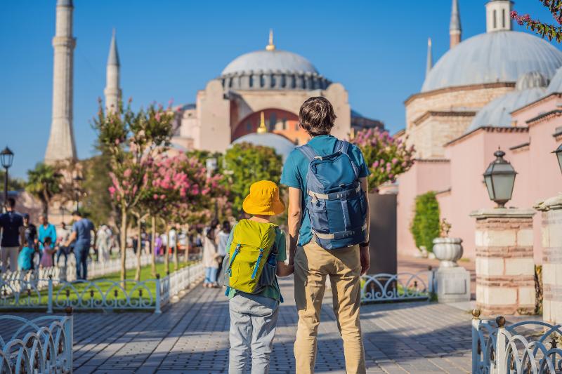 Vater und Sohn schauen auf eine Kathedrale im Early Bird Familienurlaub auf einem Steg