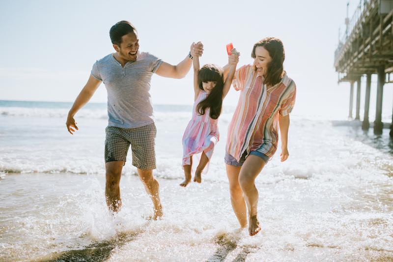 Mutter, Vater und Kind spielen gemeinsam am Strand im Familien Camp
