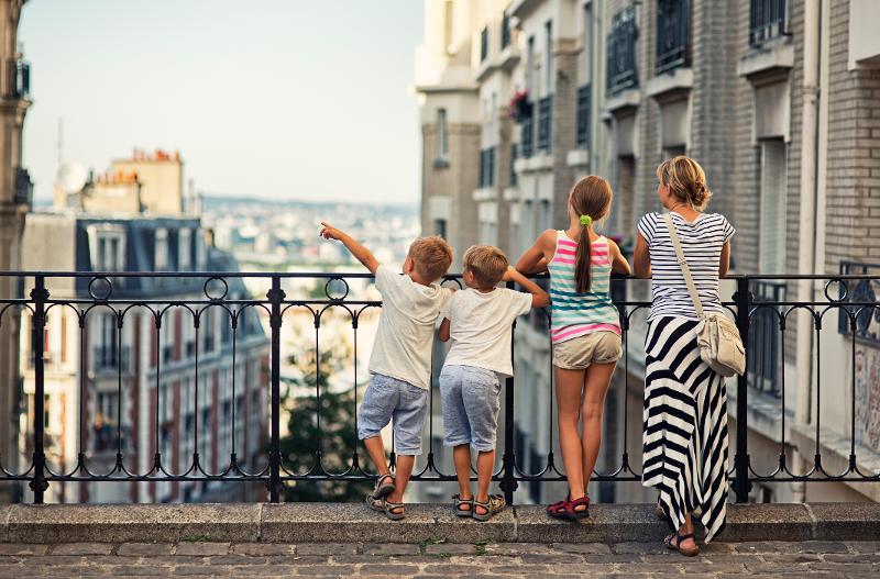 Mutter und drei Kinder genießen im Familiencamp die Aussicht auf eine Stadt
