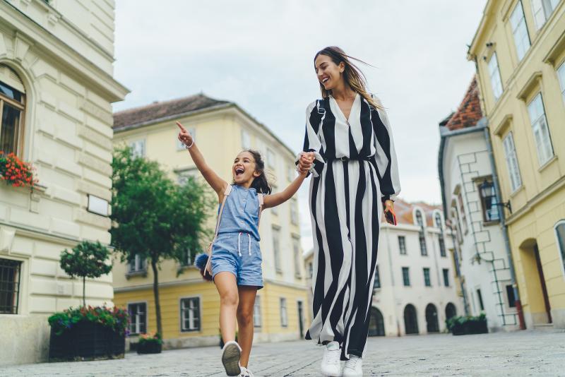 Mutter und ihr Kinder, die im Familien Kurztrip in einer Stadt umherlaufen und sich freuen