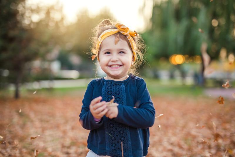Kind steht im Familien Kurzurlaub Herbstferien lachend im Laub
