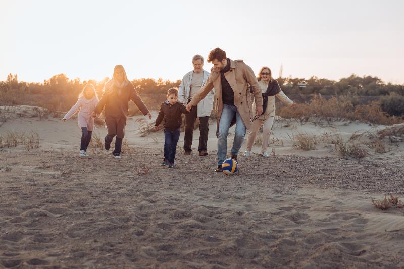 Familie läuft im Sonnenuntergang im Familien Kurzurlaub Herbstferien am Strand entlang