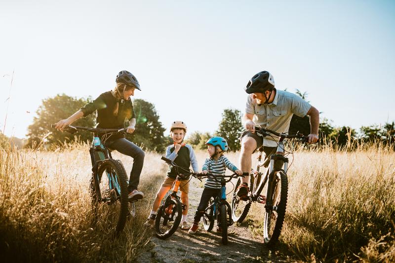 Familie fährt auf einem Feldweg mit dem Fahrrad auf Familienreisen