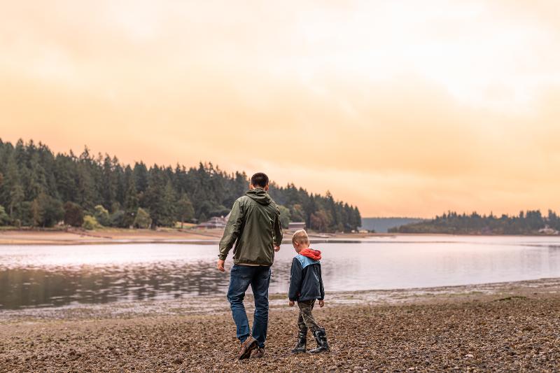 Vater und Sohn stehen auf Familienreisen Herbstferien vor einem See
