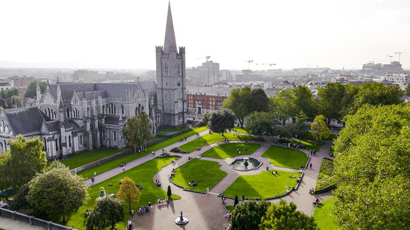Blick auf einen Platz mit vielen grünen Bäumen und Rasenflächen, sowie einer Kirche und Häusern auf der Familienreise Irland