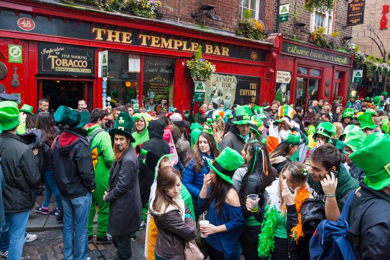 Ansammlung von Menschen die anlässlich des St Patricksday mit grünen Hüten vor einem roten Haus stehen auf eurer Familienreise Irland