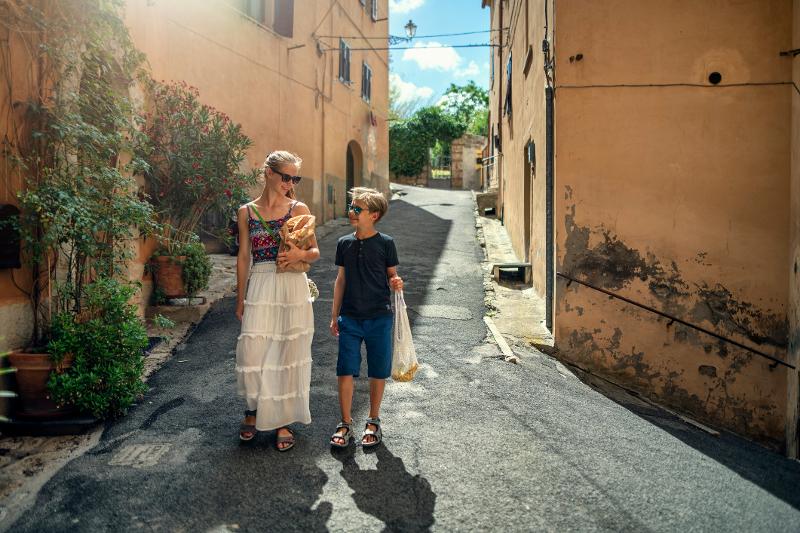 Eine Frau und ein Junge laufen zusammen bei schönem Wetter durch eine kleine Gasse, auf der Familienreise Kroatien