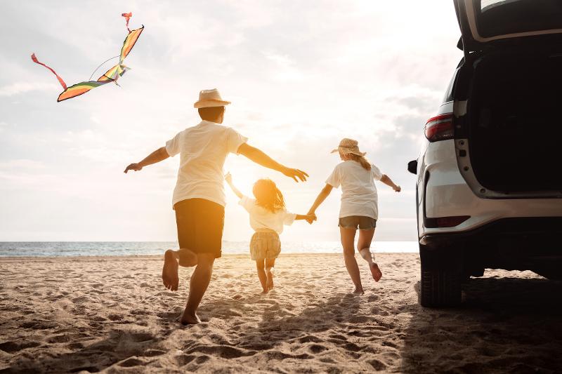 Mutter, Vater und ein Kind rennen am Strand bei Sonnenuntergang auf Familienreise