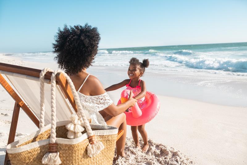 Eine Mama sitzt im Familienurlaub Balearen auf einem Liegestuhl am Strand