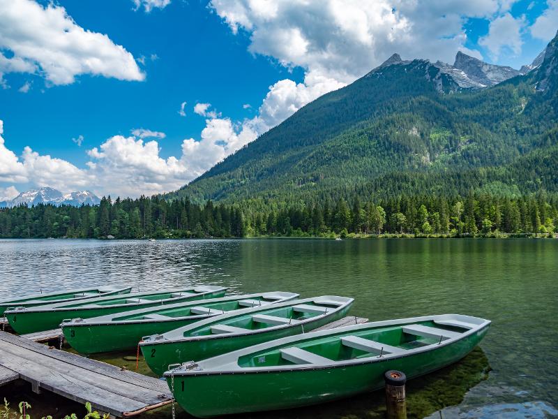 Aussicht auf den Hintersee mit Booten und den Wäldern und Bergen im Familienurlaub Bayern See