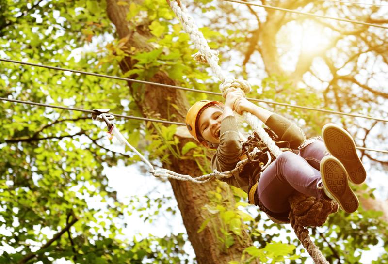 Ein Kind genießt ein Zipline-Abenteuer in einem Wald im Familienurlaub Brandenburg