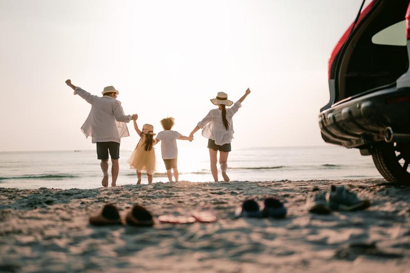 Familie am Strand neben ihrem geparkten Auto am Strand, im Familienurlaub Costa de la Luz