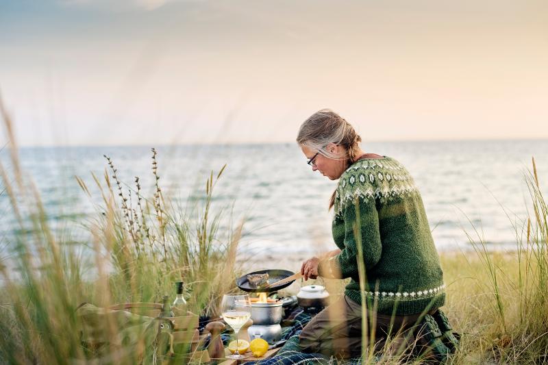 Eine Oma bereitet das Abendessen bei Sonnenuntergang vor im Familienurlaub Dänemark