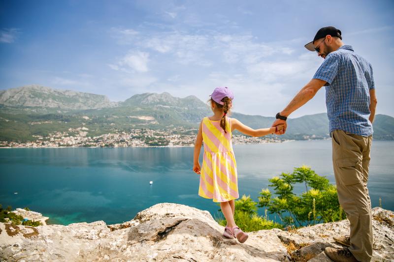  Vater mit Kind auf Felsen mit Meerblick im Familienurlaub Frankreich am Meer