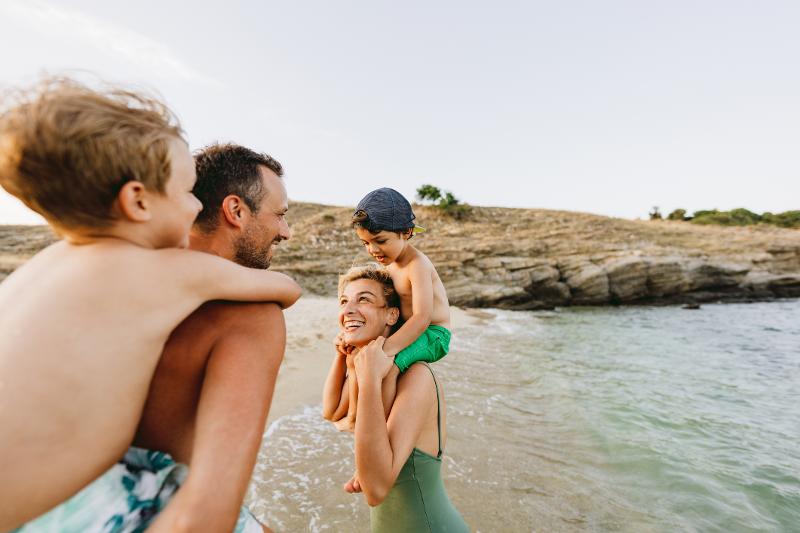  Eltern tragen Kindern Huckepack am Strand im Familienurlaub Frankreich Atlantikküste