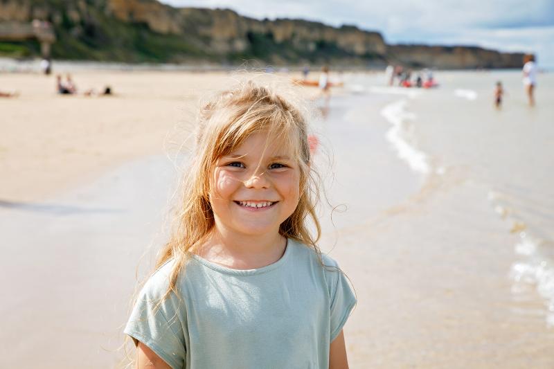  Lachendes Mädchen steht am Strand im Familienurlaub Frankreich Atlantikküste