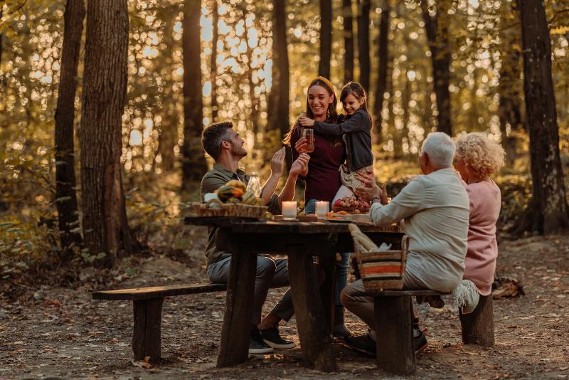 Familie picknickt gemeinsam im Wald im Familienurlaub Herbstferien