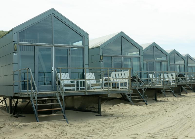 Kinder genießen den Sand während die Eltern entspannt vor der Unterkunft im Familienurlaub Holland günstig verweilen
