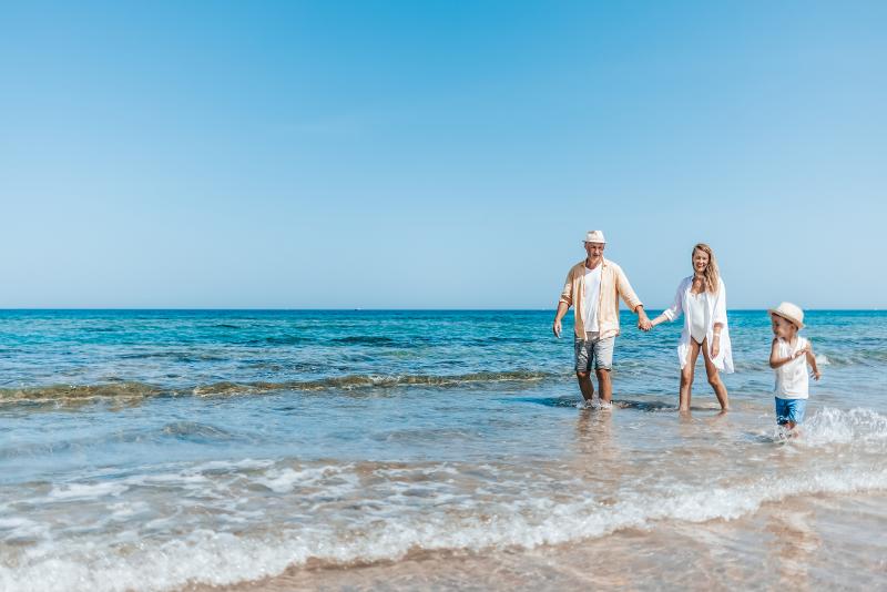 Eine Familie, die im Familienurlaub Hurghada einen Strandspaziergang direkt am Meer unternimmt