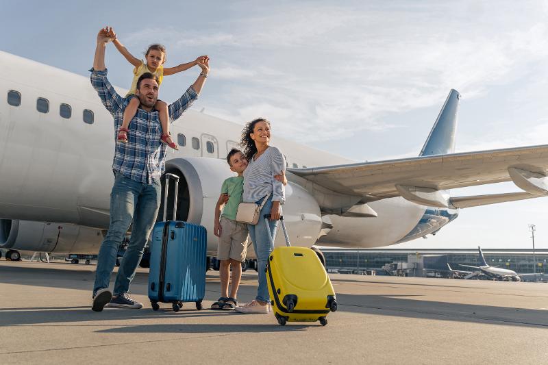  Familie mit Koffern vor dem Flugzeug im Familienurlaub ins Ausland