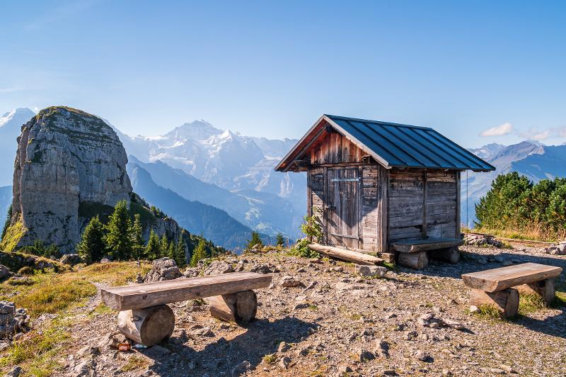 Eine Holzhütte und Bänke auf einem Berg mit einer Berglandschaft im Hintergrund im Familienurlaub in den Bergen am See