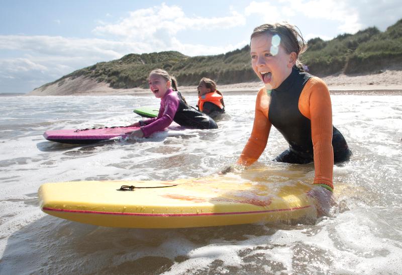  Kinder auf dem Surfboard im Wasser im Familienurlaub in England am Meer