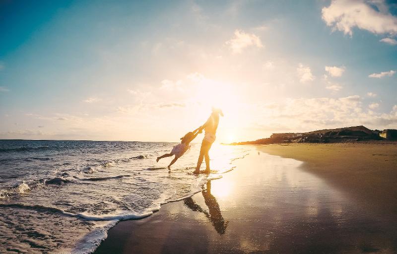  Eine Mutter spielt mit ihrem Kind am Strand bei Sonnenuntergang im Familienurlaub Italien Ferienhaus