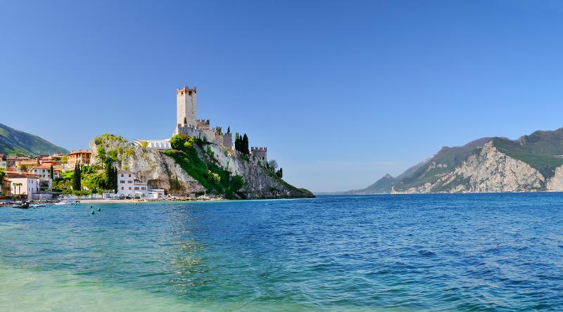 Blick auf den Gardasee mit blauem Wasser und einem Ort im Hintergrund