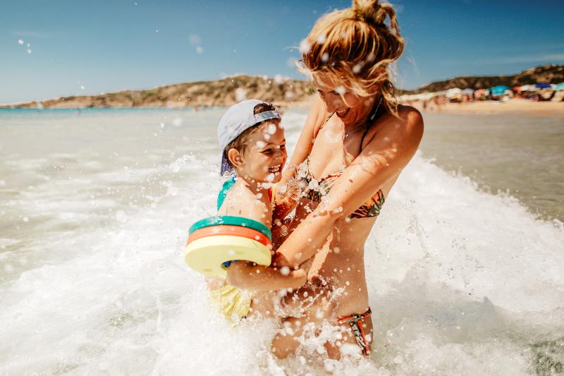  Eine Mutter und ihr Kind haben Spaß im Meer im Familienurlaub Italien am Strand