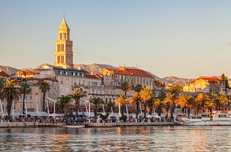 Die Stadt Split am Meer mit Promenade und Blick auf einen Kirchenturm im Familienurlaub Kroatien All Inclusive während des Sonnenuntergangs