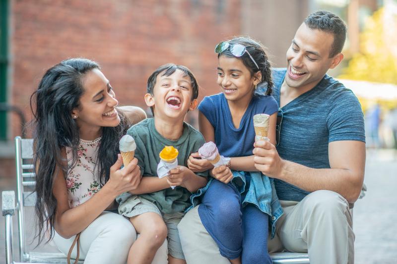 Eine lachende Familie genießt gemeinsam Eis im Familienurlaub Last Minute