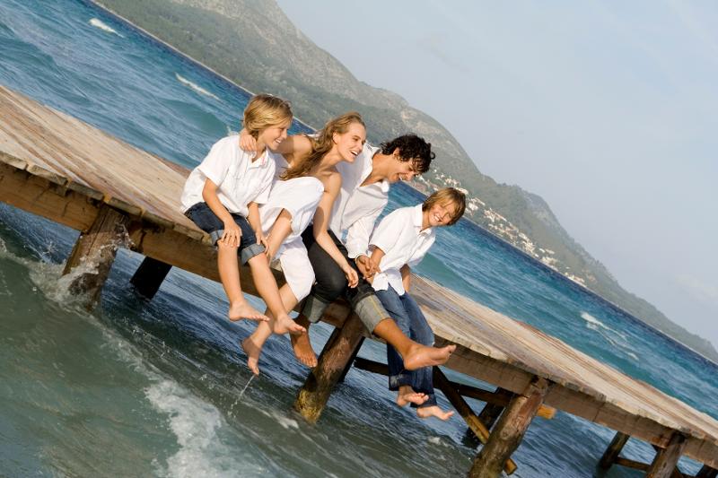 Eine Familie sitzt im Familienurlaub Mallorca auf einem Steg