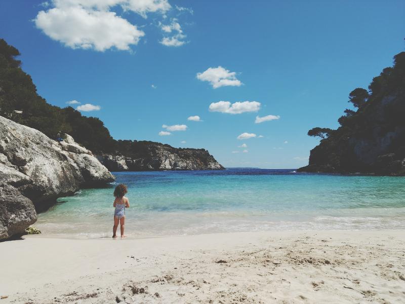 Eine Mädchen steht am Wasser im Familienurlaub Menorca