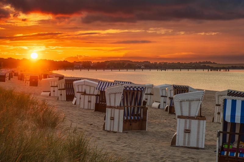 Der Sonnenuntergang scheint über den Strandkörben im Familienurlaub Last Minute Ostsee 