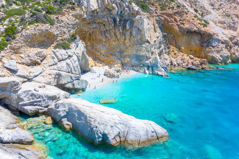 Eine Bucht im Familienurlaub Samos mit blauem Wasser und Felsen, am Strand erkennt man Menschen