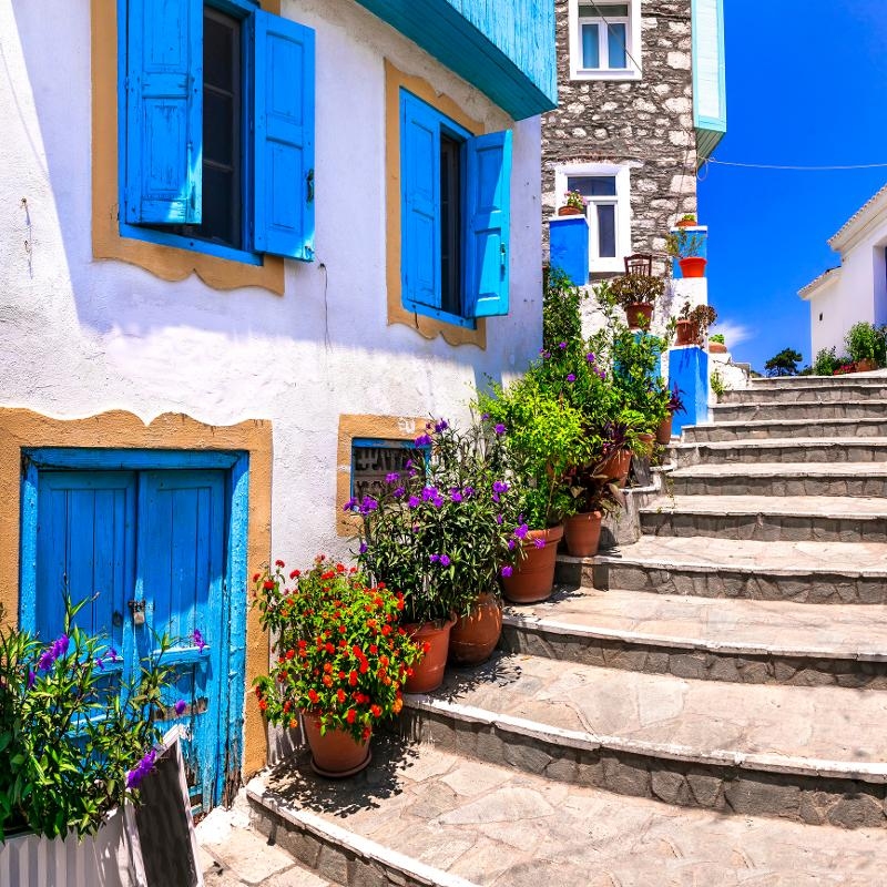 Eine Gasse mit Treppe, weißen Häusern und bepflanzten Blumentöpfen im Familienurlaub Samos