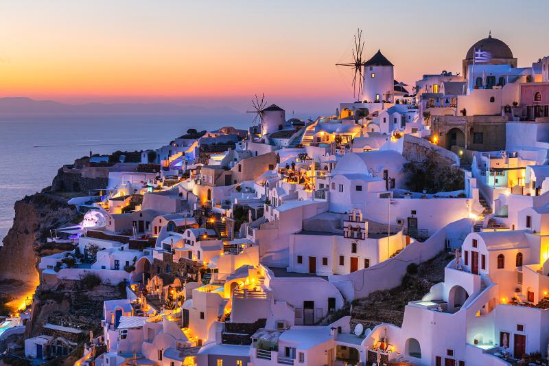 Ein Panorama aus weißen Häusern und dem Meer während des Sonnenuntergangs im Familienurlaub Santorini