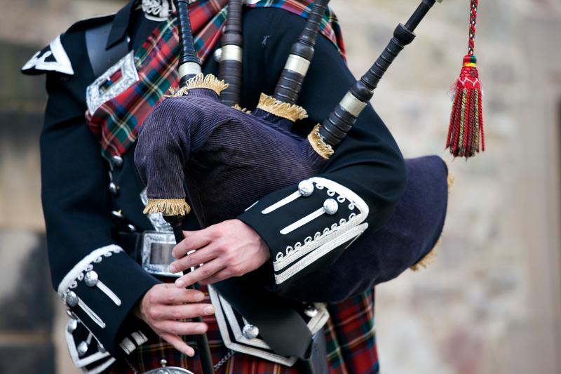 Ein Dudelsackspieler in traditioneller schottischer Kleidung im Familienurlaub Schottland