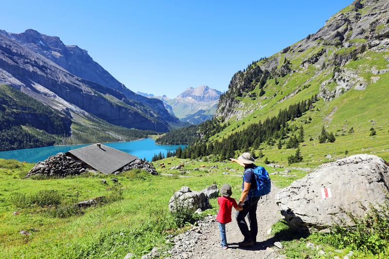 Familie beim Wandern auf einem Pfad in den Schweizer Alpen mit beeindruckender Bergkulisse.