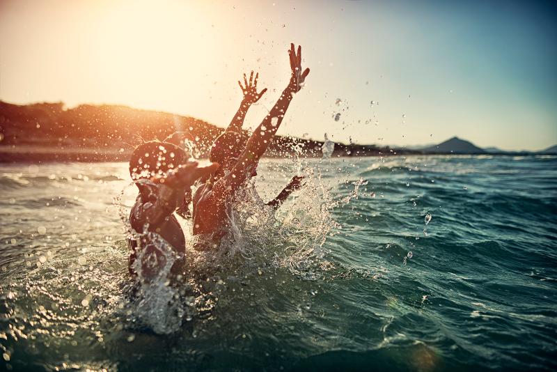 Zwei Kinder, die im Familienurlaub Spanien am Meer schwimmen gehen und im Wasser planschen