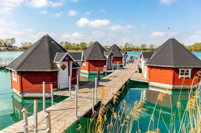 Mehrere rote Häuser auf einem See im Familienurlaub Thüringer Wald All Inclusive