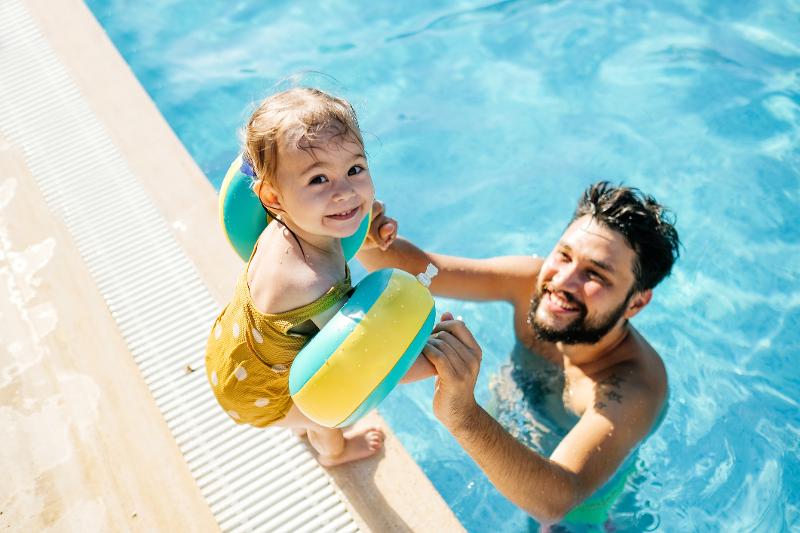 iEn kleines Mädchen wird von ihrem Vater im Pool im Familienurlaub Türkei festgehalten