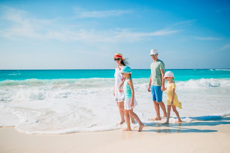 Eine Familie mit zwei Kindern, die im Familienurlaub Zakynthos einen Spaziergang am Strand unternimmt