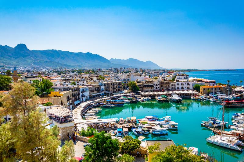 Ausblick auf eine Stadt mit Hafen in dem Boote geparkt sind und im Hintergrund Berge und das Meer im Familienurlaub Zypern All Inclusive