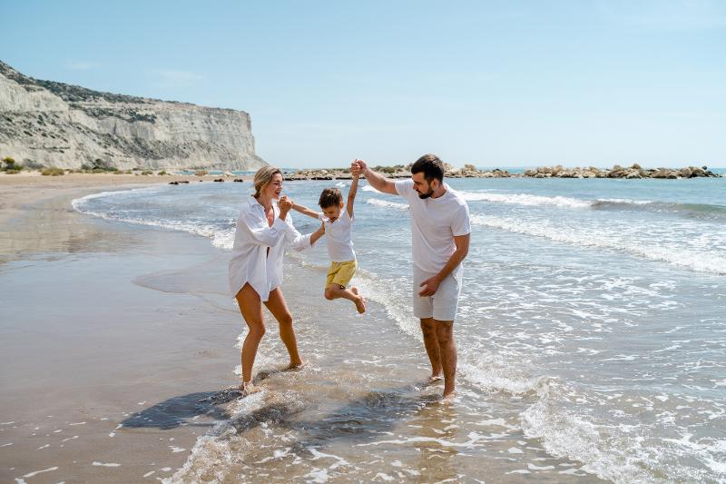 Ein Pärchen, welches am Strand mit ihrem Sohn im Familienurlaub Zypern spielt