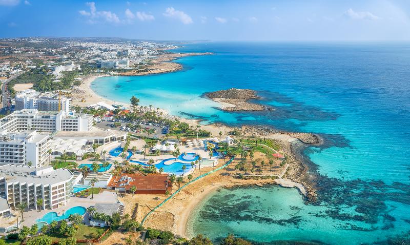 Ausblick auf eine Hotelanlage direkt am Meer mit einer großen Poollandschaft im Familienurlaub Zypern