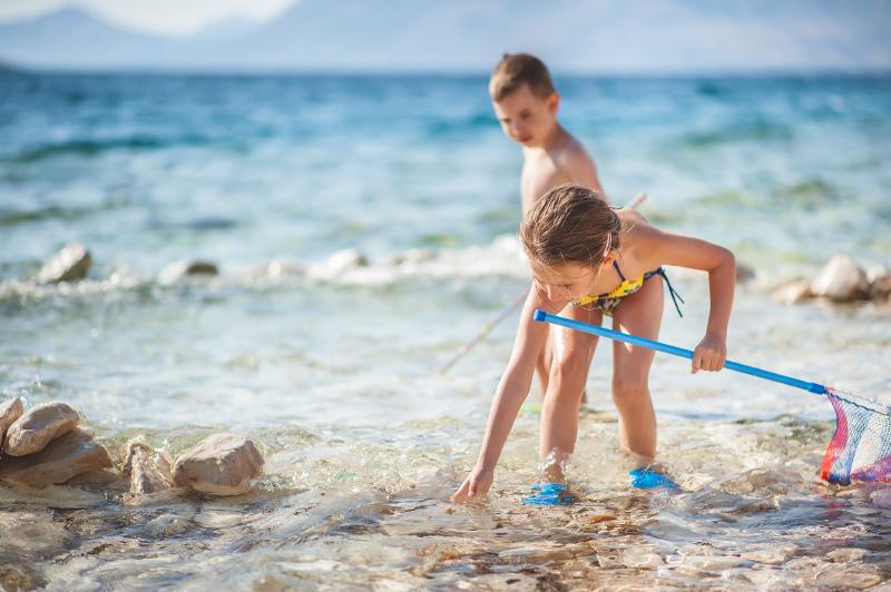 zwei Kinder spielen im flachen Wasser im günstig Familienurlaub Kroatien.