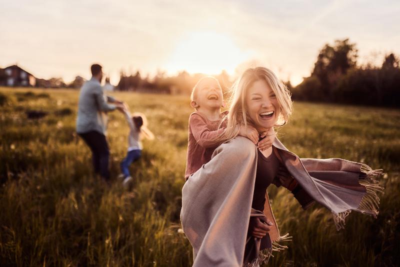 Familie spielt im Herbstferien Familienurlaub günstig auf einem Feld im Sonnenuntergang