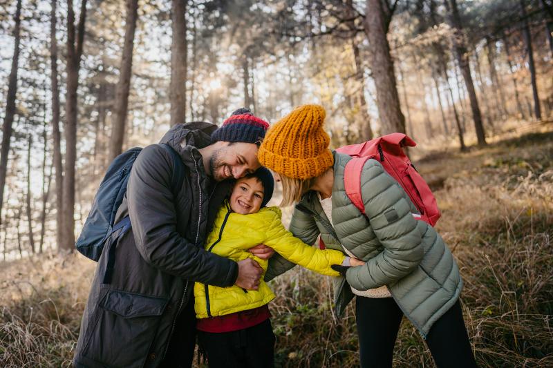 Mutter, Vater und Sohn haben im Herbsturlaub mit Kindern zusammen Spaß im Wald