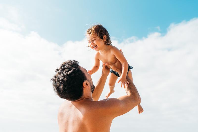 Ein Junge hat mit seinem Vater Spaß am Strand im Ibiza Urlaub mit Kindern